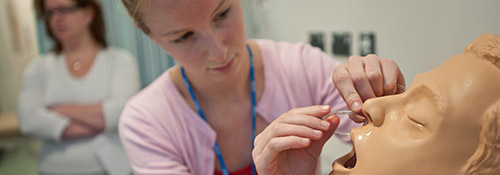 medical student practicing on a plastic medical training manikin