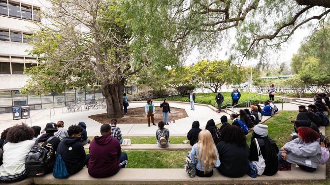 Student tour guides speak to a tour group in front of the library