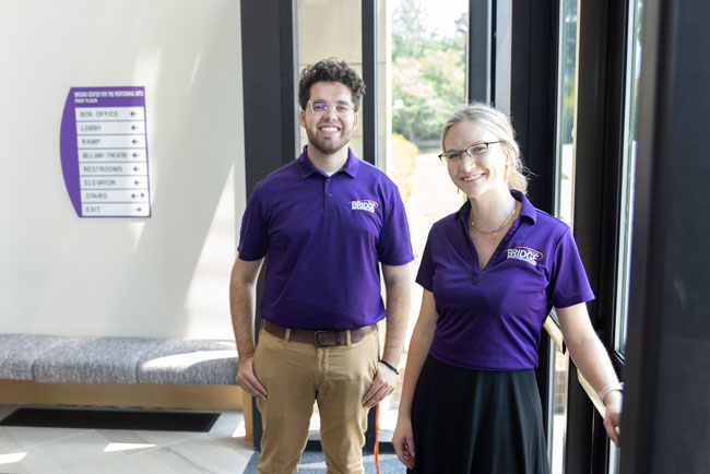 A male and female Bridge orientation ambassidor pose wearing shirts with the Bridge to Clemson logo