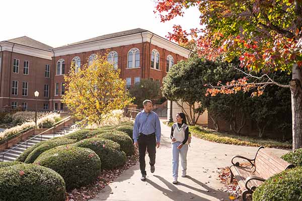 A professor and student walking together on campus. 