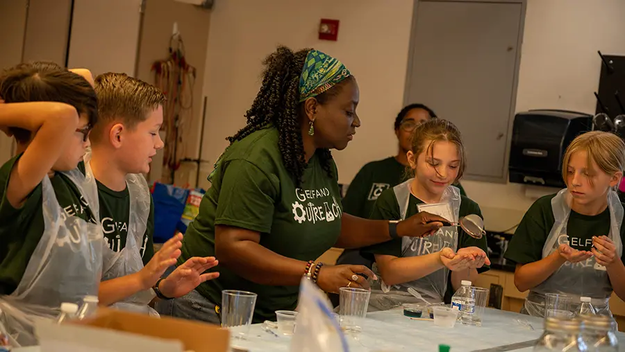 A woman working at a lab table with children on either side