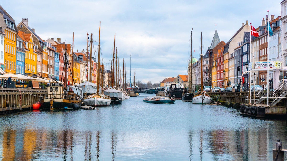 A canal with sailboats lined by colorful buildings on both sides.