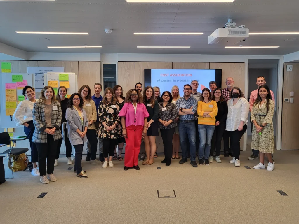 Group photo of 40+ people standing together in a meeting room