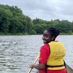 A color photo of a woman looking back while in a canoe