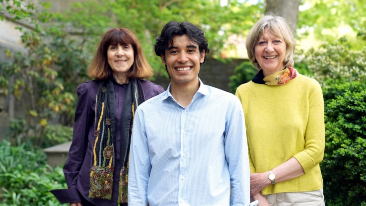 Student standing between two female faculty members outside