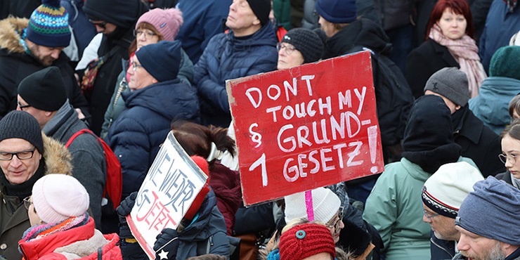 Menschenmenge; in der Mitte wird ein rotes Schild mit der Aufschrift: DONT TOUCH MY GRUNDGESETZ § 1 hochgehalten.