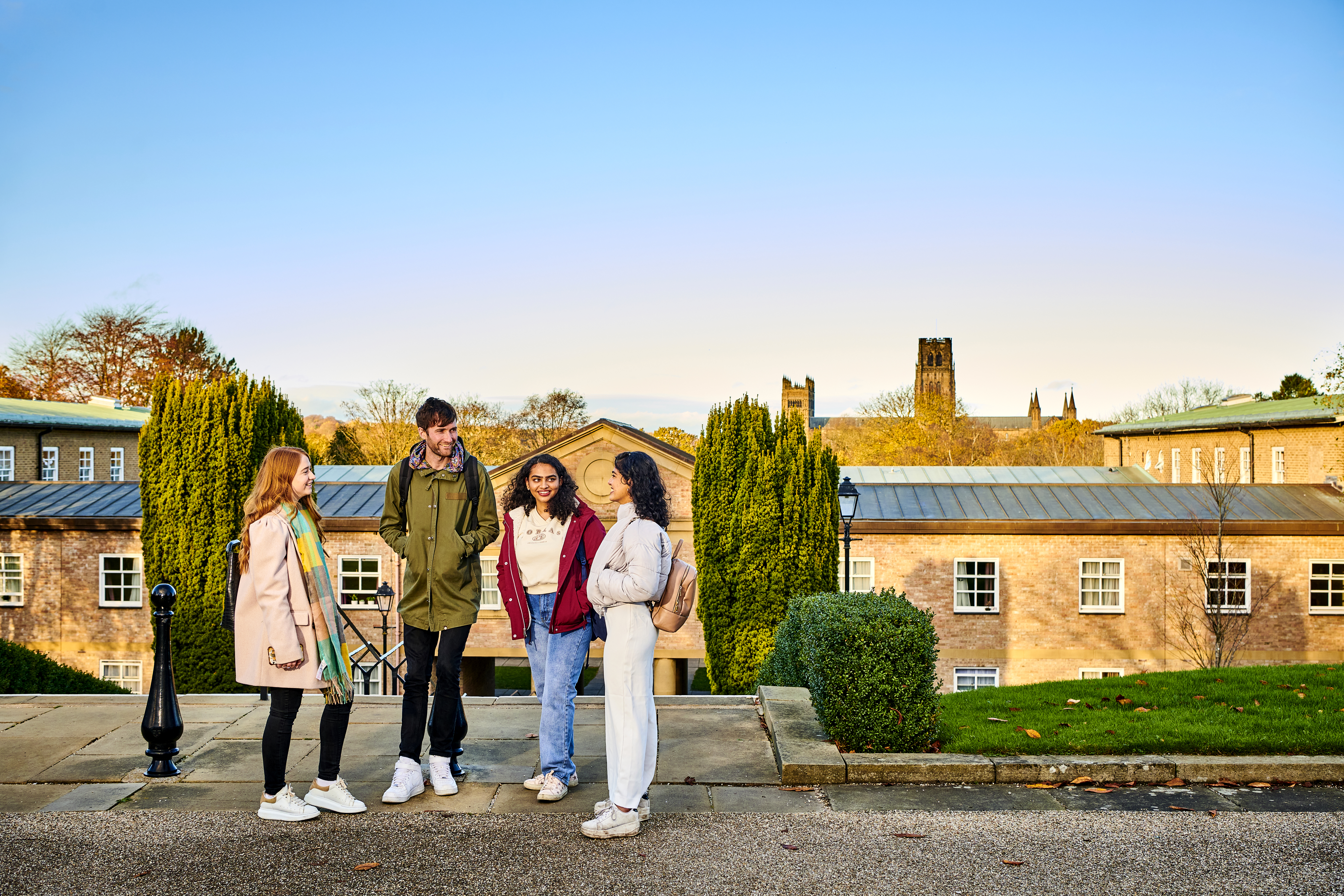 An image of 4 students standing outside on the grounds of St Mary's on a sunny day with Durham Cathedral in the background