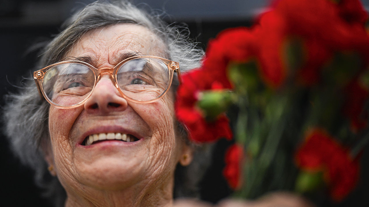 Celeste Caeiro at age 90 holds a bouquet of carnations during a military parade to celebrate the Carnation Revolution's 50th anniversary in Lisbon, Portugal  on April 25th 2024