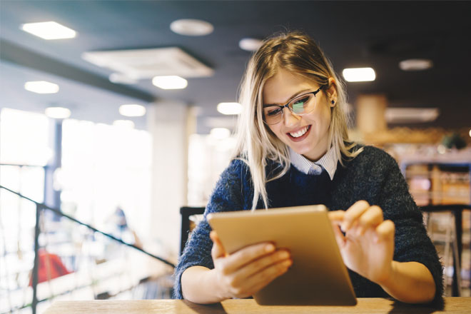 Woman sat down in library studying on tablet