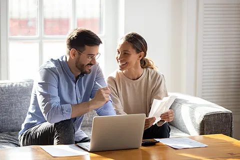 couple sitting on sofa in front of laptop