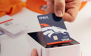 Hand making a payment with a Denver Broncos debit card