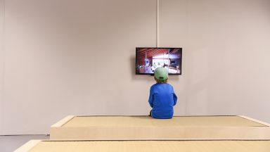 Un enfant, de dos, face à un écran dans ue grande salle vide d'Archizoom, durant la Nuit des Musées 2015