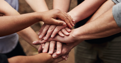 Photo of diverse group of people bringing their hands together.