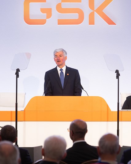 GSK Chair, Jon Symonds speaks, at podium on stage, at 2024 AGM