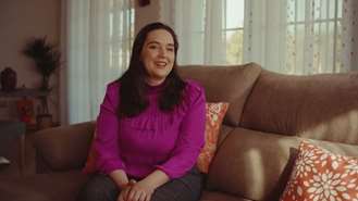 Angeles sitting on a sofa in a pink shirt