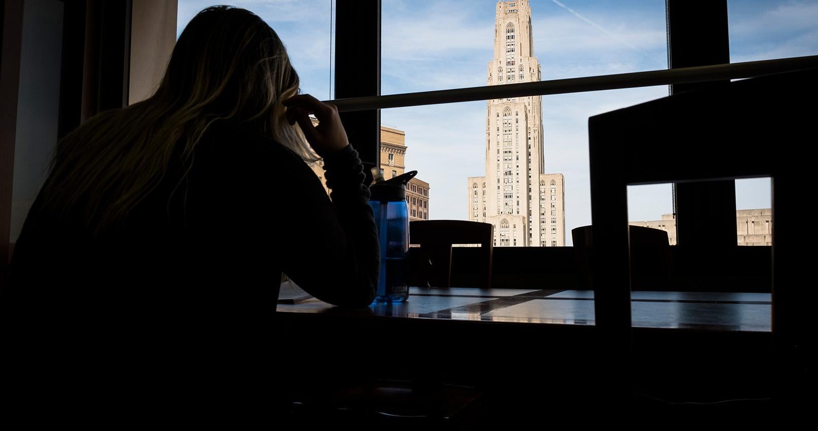 Student looking toward the Cathedral of Learning from afar