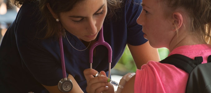 nurse with stethoscope giving a shot to a young patient