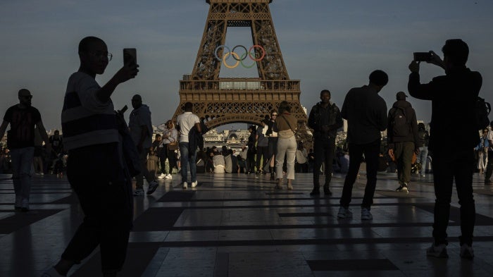 People take photos of the olympic rings at the Eiffel Tower