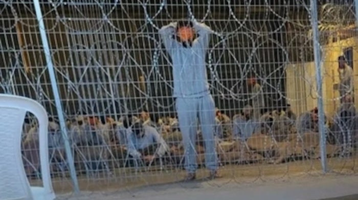 A leaked photograph of the detention facility at the Sde Teiman military base shows a blindfolded man with his arms above his head. Interviewed healthcare workers described this image as punishment imposed by Israeli soldiers on Palestinian detainees if they speak or move. 