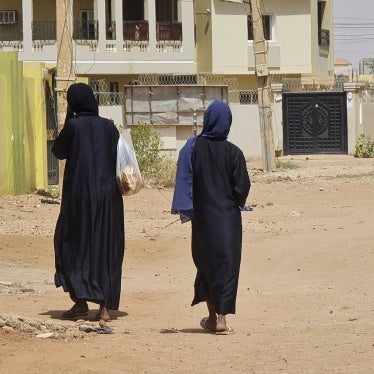 Two unidentifiable women walk down a city street 