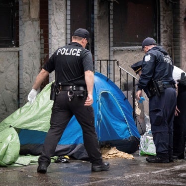 Police look into a tent at an encampment for unhoused people