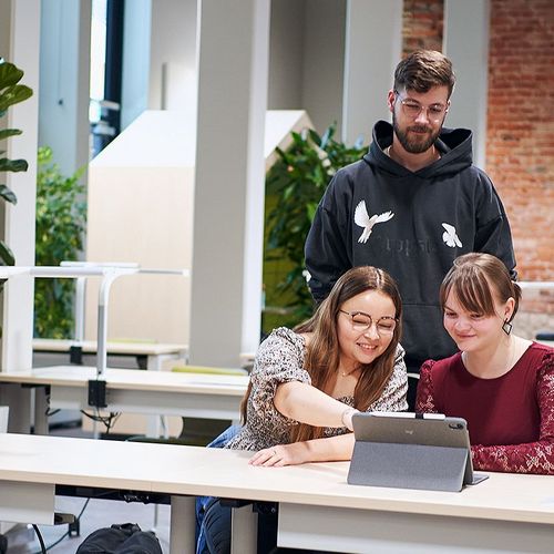Drei Studierende der Verwaltungsökonomie schauen in der Bibliothek der Hochschule Harz auf ein Tablet.