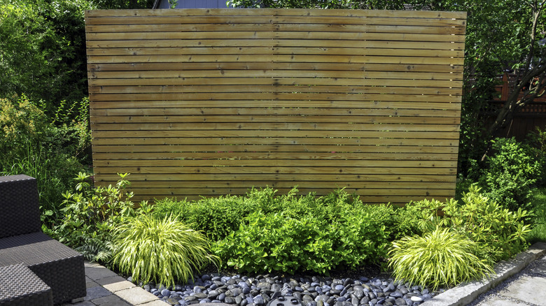 outdoor slat privacy wall with greenery and outdoor furniture