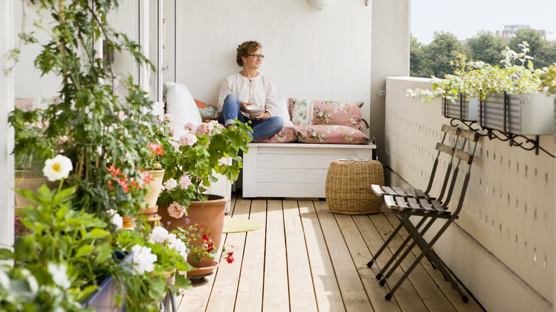 woman surrounded by plants sitting on porch with basket storage visible