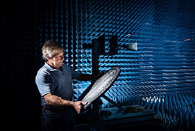 Male scientist working in a dark blue room with tech