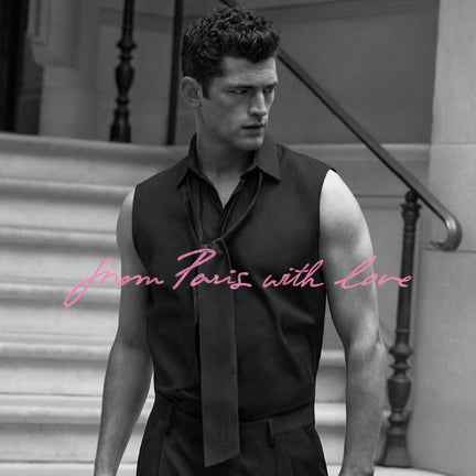 Man in a sleeveless black shirt with a tie standing on steps, text 'From Paris with Love' in pink.