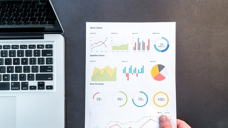 image of charts and graphs next to a laptop computer