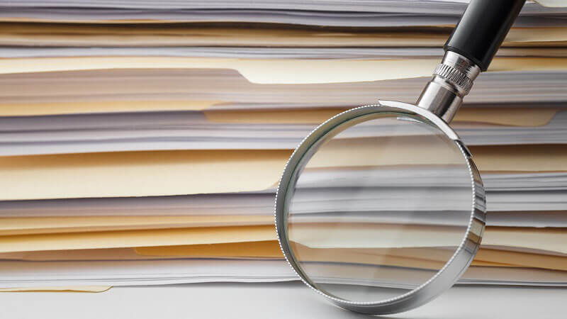 image of a magnifying glass next to stack of folders