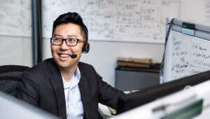 a man standing in front of a laptop with headset