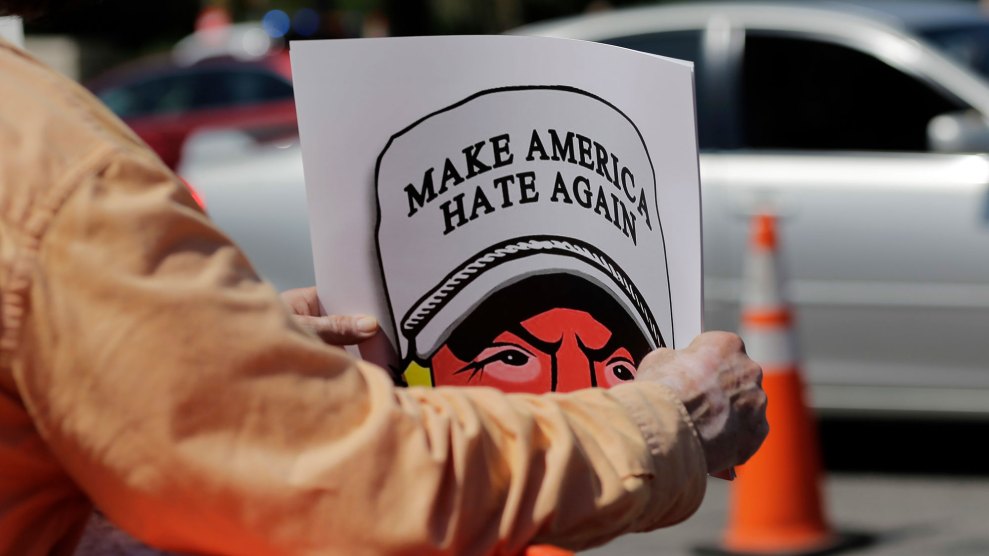 Man holding sign of Trump wearing Make America Hate Again hat