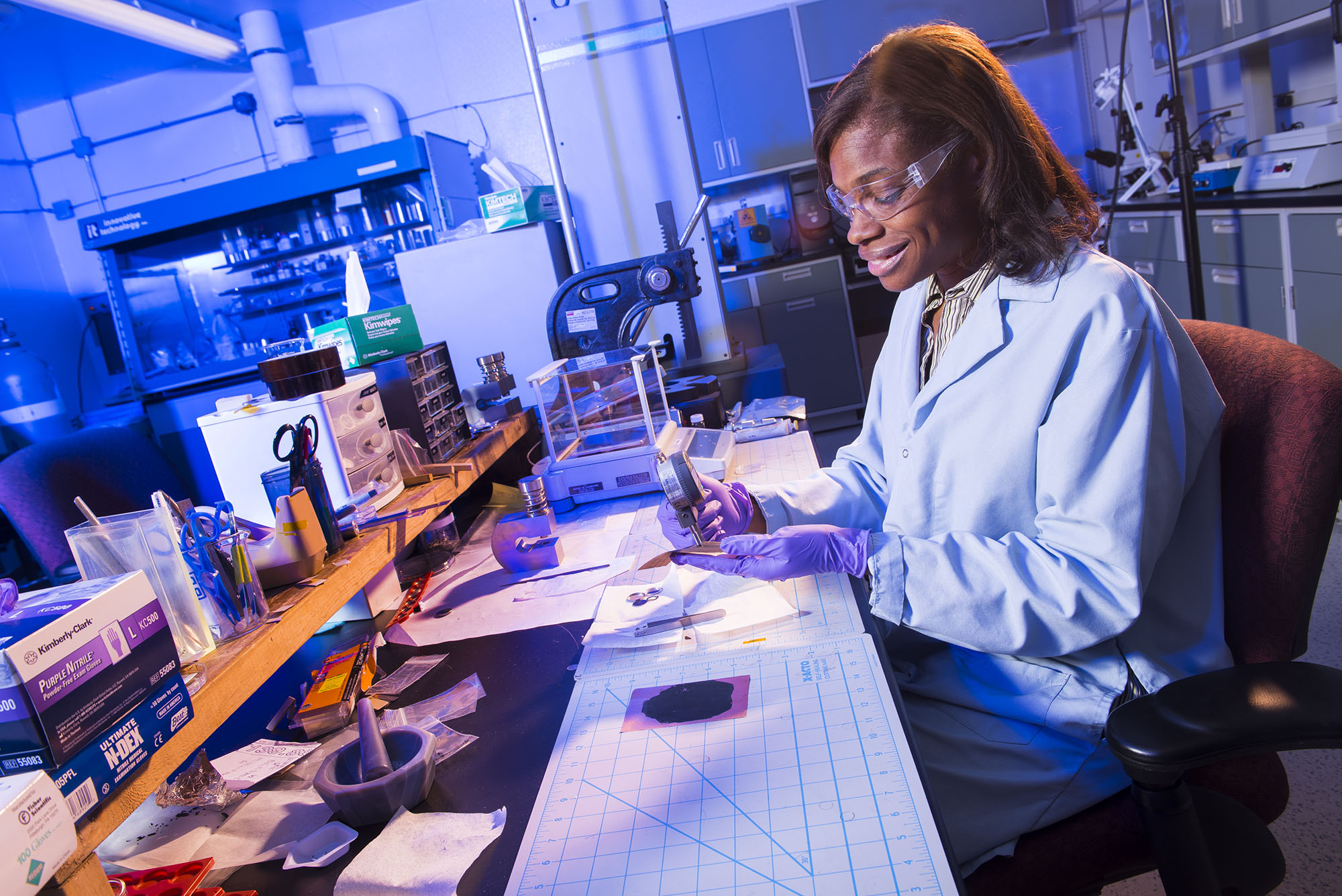 Female researcher at a lab table conducting tests on materials.