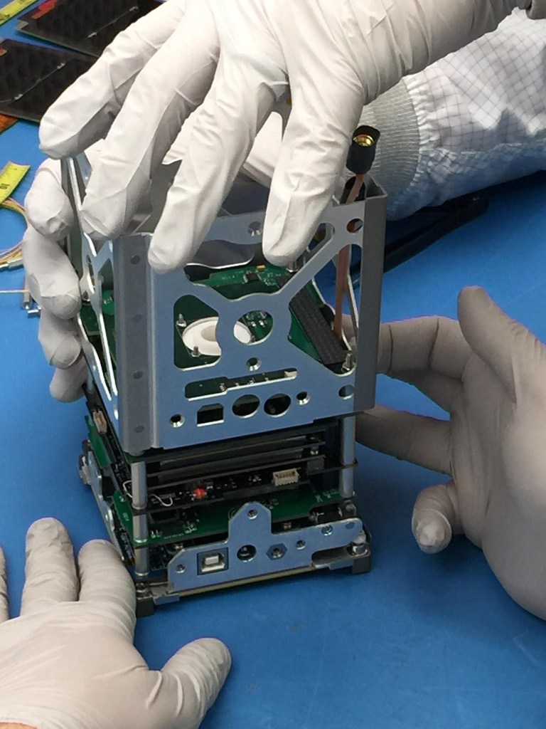 Close Up picture of two peoples' hands assembling a small device.