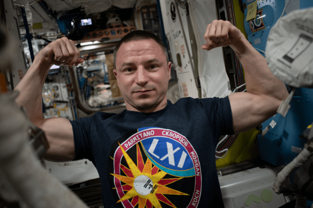 Flight Engineer Drew Morgan strikes a pose (flexing his muscles) in the Quest Airlock (A/L) during preparations for Extravehicular Activity 61 (EVA 61)