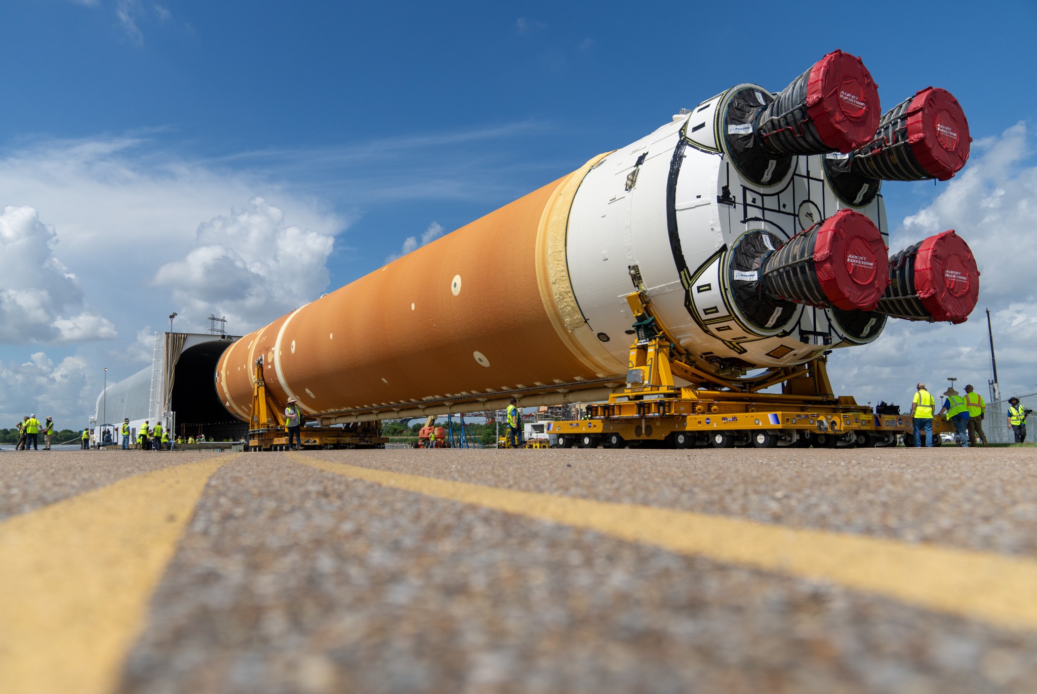 An image showing the core stage of the SLS rocket being moved out of NASA's Michoud Assembly Facility in New Orleans and towards the agency's Pegasus Barge which will transport it to NASA's Kennedy Space Center in Florida.