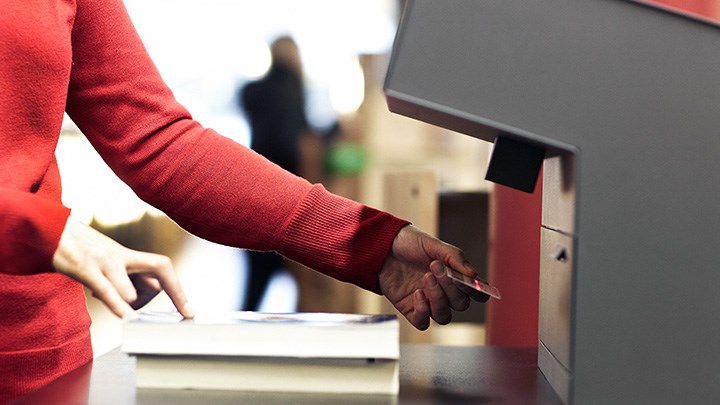 Photo of a person using one of the library lending machines.