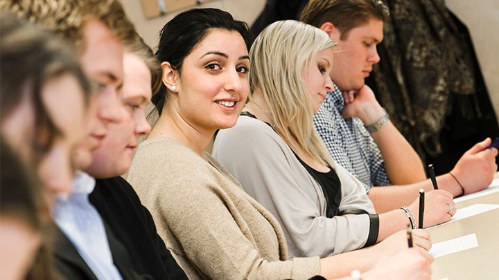 Photo of students sitting in a row and writing.