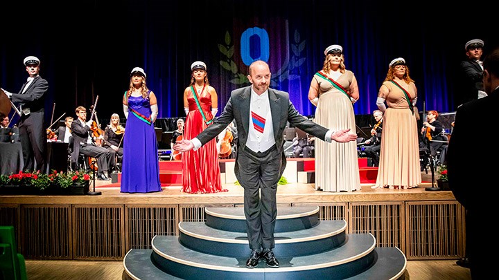 Master of Ceremonies Henrik Scander in front of students in formal dress.