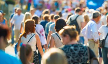 Crowd of people walking on the sunny and busy city street in soft focus