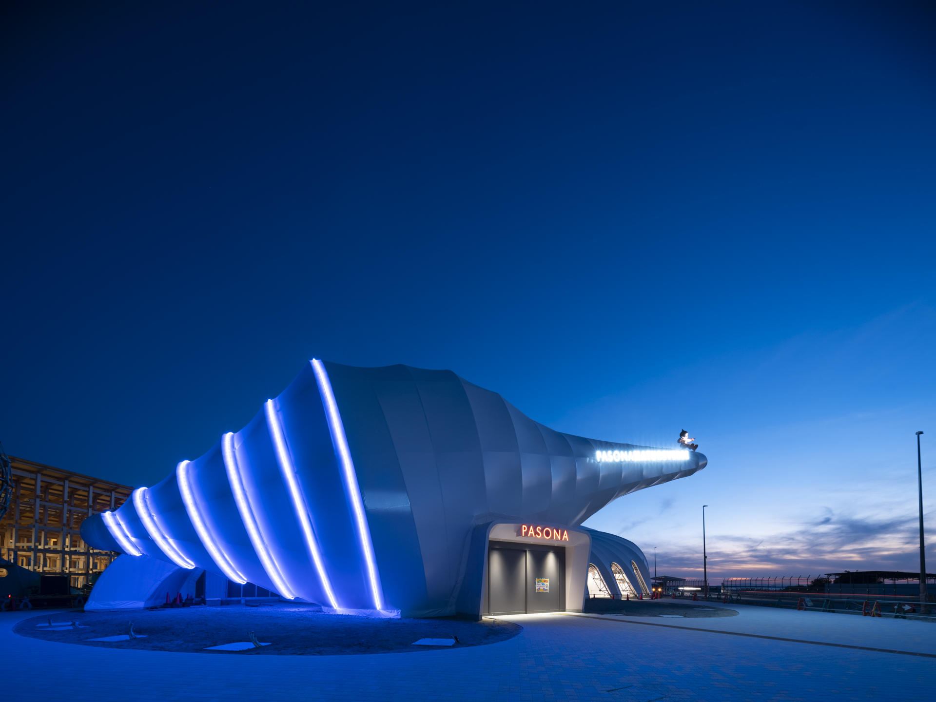  夜になると巻貝棟がライトアップされ、らせん状にいのちの光が輝きます。  At night, the pavilion's shell building is lit up and the light of life shines in a spiral pattern. 