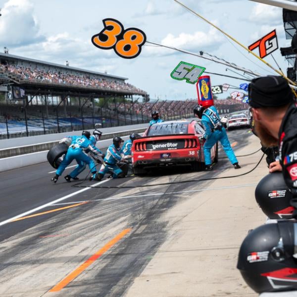 A pit crew changes a tire on a red racecar