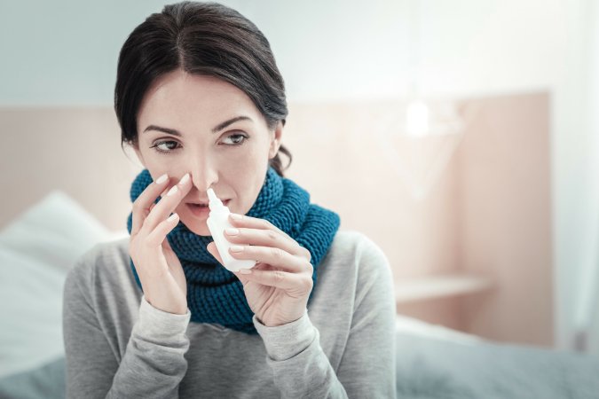 A woman administers a nasal spray