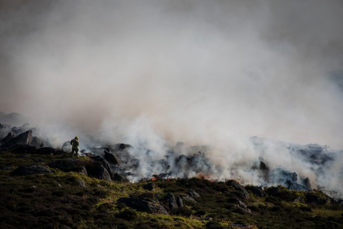 firefighters standing in front of smoky hillside