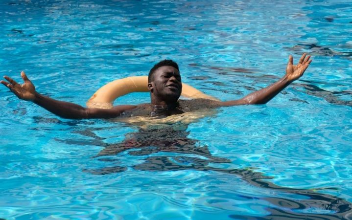 A happy man floating on water with his eyes closed.