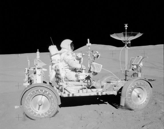 Apollo 15 astronaut on lunar rover in black and white NASA image