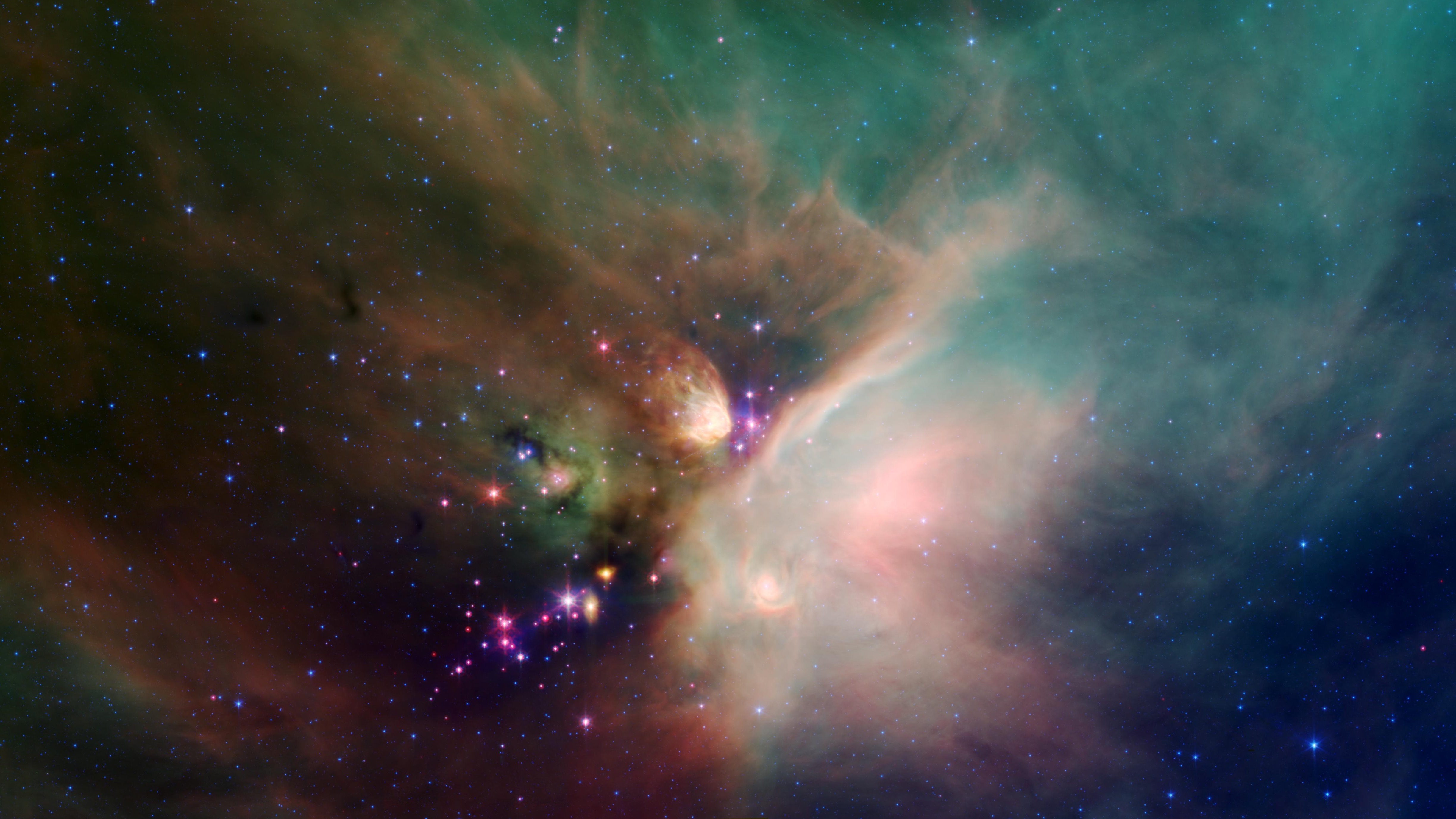 Newborn stars peek out from beneath their natal blanket of dust in this dynamic image of the Rho Ophiuchi dark cloud from NASA's Spitzer Space Telescope.