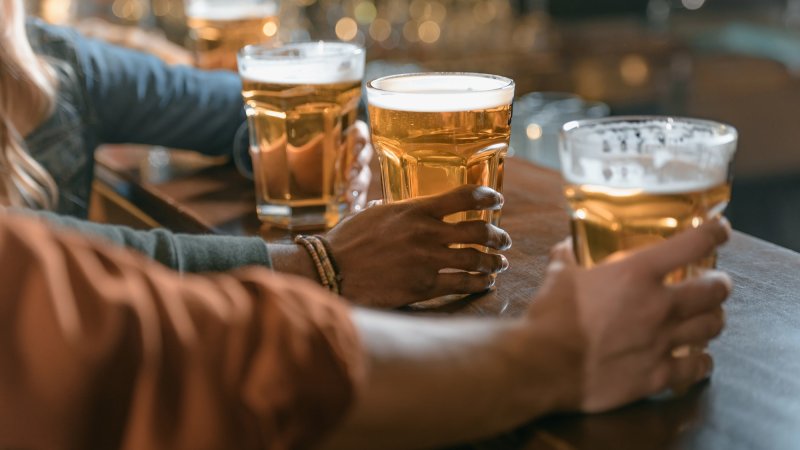 Three people's hands holding beers at bar